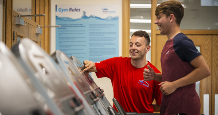 Sports and fitness instructor advising person on a treadmill 